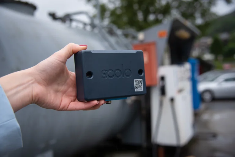 Hånd som holder en Soolo Master med en drivstofftank i bakgrunnen. Dette er Soolo fjernpeiling.